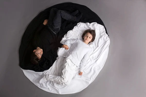 两个黑白相间的孩子躺在阴阳圆圈的地板上 形成了一个孤立的形象 — 图库照片