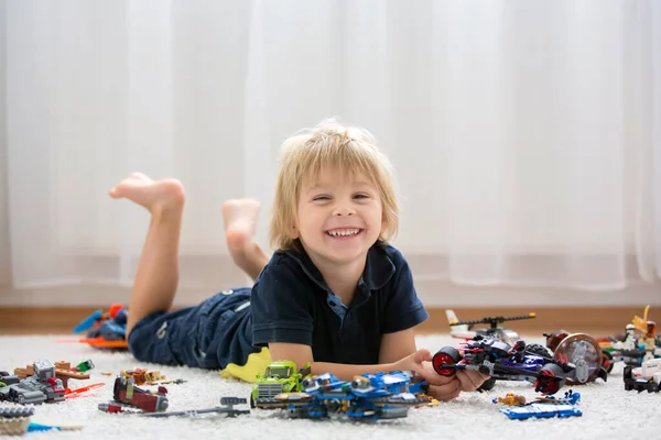 かわいい幼児の子供 ブロンドの男の子 カラフルなプラスチックブロック 建設おもちゃ 車や飛行機を作って遊ぶ — ストック写真