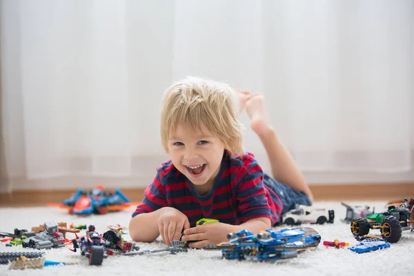 かわいい幼児の子供 ブロンドの男の子 カラフルなプラスチックブロック 建設おもちゃ 車や飛行機を作って遊ぶ — ストック写真