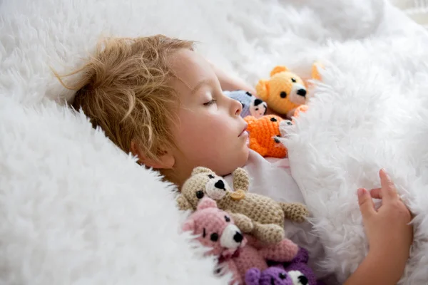 小さな幼児の子供 かわいいブロンドの男の子 多くのテディベアと寝て 手作りAmigurumiおもちゃで自宅でベッド — ストック写真