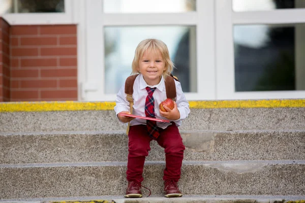早熟金发碧眼的孩子 穿着制服的可爱男孩 拿着苹果和书本 暑假后第一次上幼儿园 — 图库照片