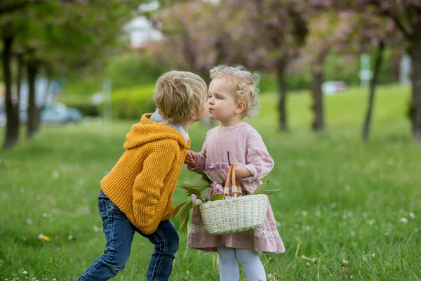 美しい子供たち 幼児の男の子と女の子は 一緒に桜の庭で遊んで 男の子は女の子に野生の花の小さな花束を与えます 子供の友情 幸せな子供時代 — ストック写真