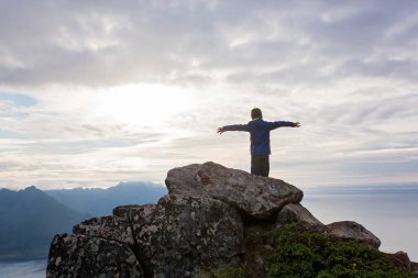 Şirin bir çocuk, bir kayanın üzerinde duruyor ve Kuzey Norveç 'teki Senja Adası' ndaki Segla dağına bakıyor. Norveç 'in İskandinav topraklarında inanılmaz güzel manzara ve görkemli doğa