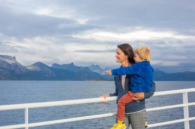 Çocuk ve anne, annesiyle birlikte güzel sarışın çocuk Nortern Norveç 'te Lofoten' e giden bir feribottan dağlara bakıyor.