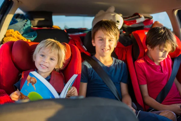 孩子们 孩子们 兄弟姐妹们 开车去度假 坐在车座上看书 玩手机 — 图库照片