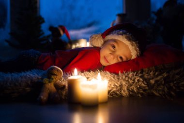 Güzel çocuk, evlat, Noel arifesinde pencerenin önünde Noel Baba 'yı merakla bekliyor.