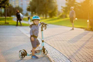 Yaz zamanı, gün batımında motosikletle parkta oynayan tatlı bir anaokulu çocuğu.