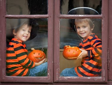 Jack-o-lantern ile bir pencere üzerinde oturan iki yakışıklı çocuk