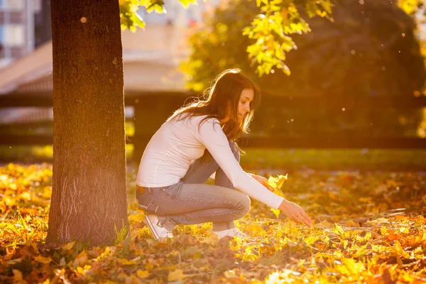 Νεαρή γυναίκα που κάθεται δίπλα σε ένα δέντρο σε ένα πάρκο — Φωτογραφία Αρχείου