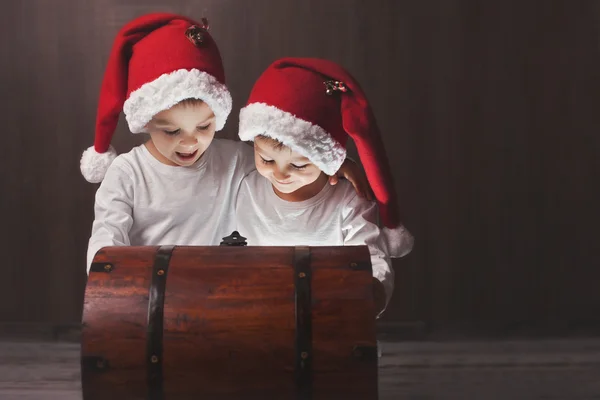 Dos chicos adorables, abriendo el pecho de madera, brillando luz de insi —  Fotos de Stock