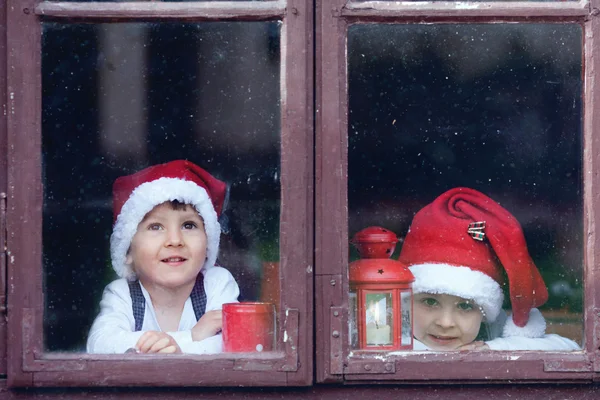 Dwa cute chłopców, patrząc przez okno, czekając na Santa — Zdjęcie stockowe