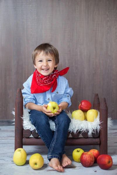 Porträt eines glücklichen kleinen Jungen, der Äpfel isst und auf einem Baby sitzt — Stockfoto