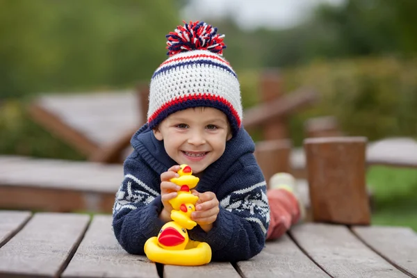 Menino adorável, brincando com patos de borracha lá fora em um aut — Fotografia de Stock