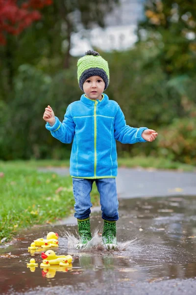 小さな男の子が、泥だらけの水たまりにジャンプ — ストック写真