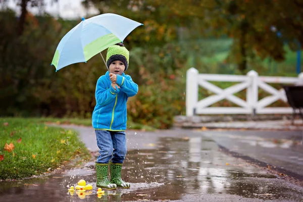 小さな男の子が、泥だらけの水たまりにジャンプ — ストック写真