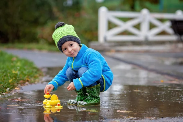 Liten pojke, hoppa i leriga pölar — Stockfoto