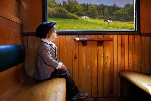 Rapaz, vestido de casaco e chapéu vintage, sentado num comboio — Fotografia de Stock