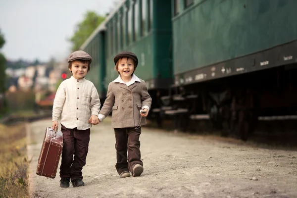 Dois meninos, vestidos com roupas vintage e chapéu, com mala — Fotografia de Stock