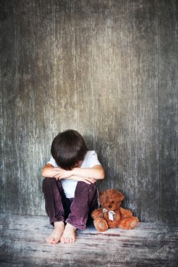 Young boy, sitting on the floor, teddy bear next to him, crying clipart