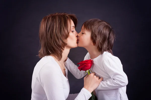 Jovem garoto dando lindo rosa vermelha para sua mãe — Fotografia de Stock