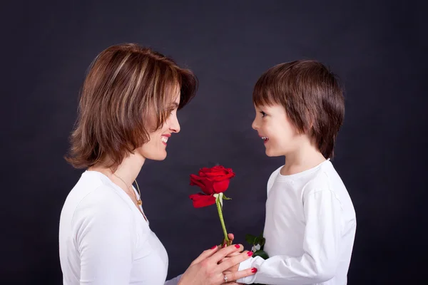 Joven niño dando hermosa rosa roja a su mamá —  Fotos de Stock