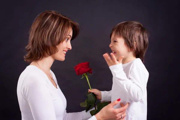 Fiatal gyerek, amely gyönyörű vörös rózsa, hogy az anyja — Stock Fotó