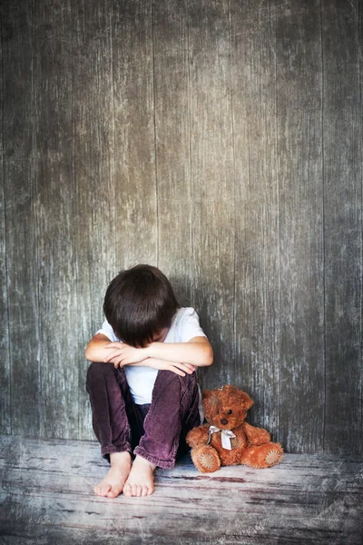 Młody chłopak, siedząc na podłodze, misia obok niego, płacz — Zdjęcie stockowe