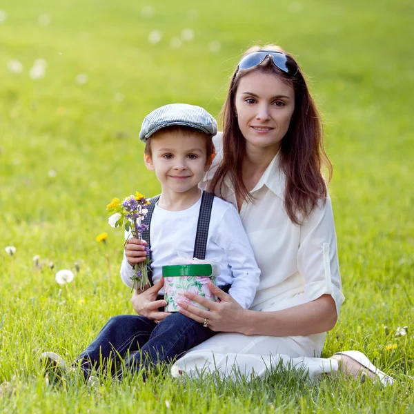 Criança bonita e mãe no parque de primavera, flor e presente. Mães — Fotografia de Stock