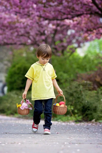 Niño dulce, llevando dos cestas con flores y huevos, caminar — Foto de Stock