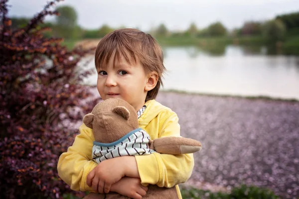 Очаровательный мальчик, держит игрушечного друга в парке — стоковое фото