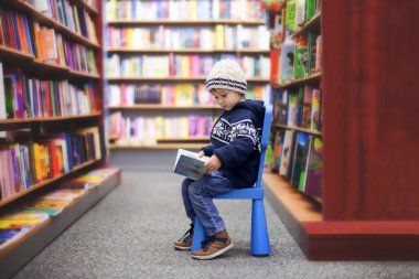 Adorable little boy, sitting in a book store clipart