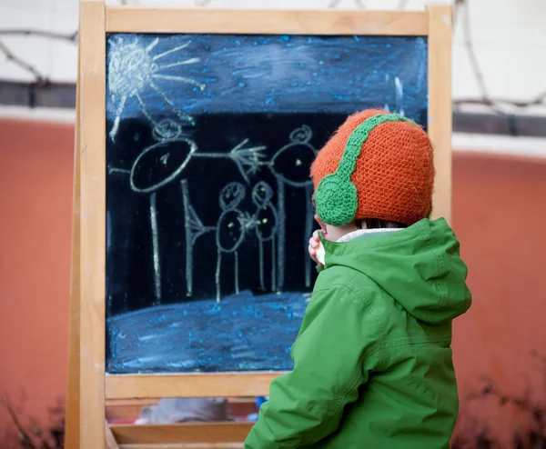 Очаровательный маленький мальчик, рисует летнюю картину с мелом на кабане — стоковое фото
