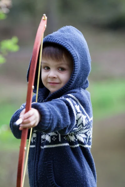 Menino atira com arco em um alvo, ao ar livre — Fotografia de Stock