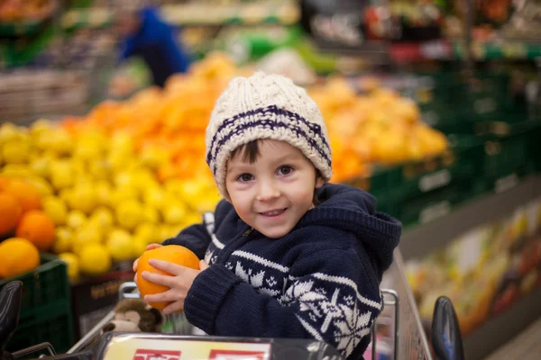 Entzückender kleiner Junge, der in einem Einkaufswagen sitzt — Stockfoto