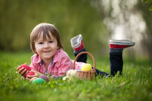 Milý chlapeček se těší jeho velikonoční vejce v parku — Stock fotografie