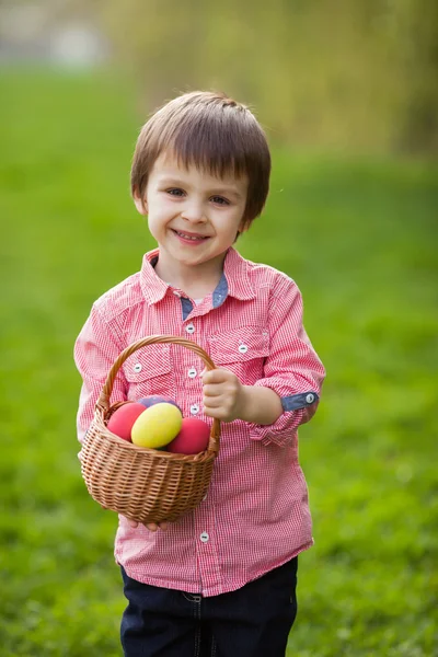 Ładny chłopczyk, trzymając kosz z kolorowych pisanek — Zdjęcie stockowe