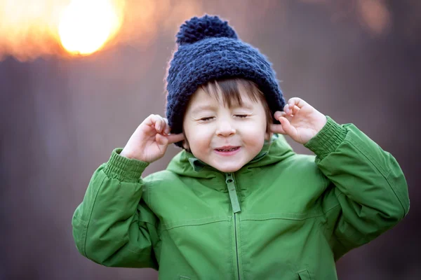 Small boy holds his hands over ears not to hear, making sweet fu — Stock Photo, Image