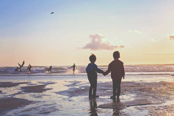 Σιλουέτα της δύο παιδιά, παρακολουθώντας σέρφερ στην παραλία — Φωτογραφία Αρχείου