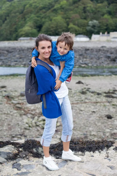 Retrato de la madre, sosteniendo a su hijo, sonriendo a la cámara — Foto de Stock