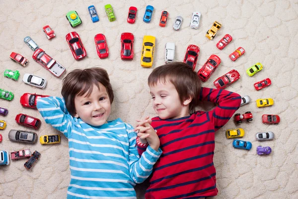 Garotos adoráveis, deitados no chão, carros de brinquedo ao seu redor, olhe — Fotografia de Stock