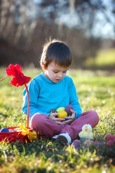 Adorable boy in the park, having fun with colored eggs for Easte — Stock Photo, Image