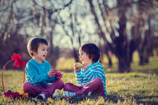 Dos chicos en el parque, divirtiéndose con huevos de colores para Pascua — Foto de Stock