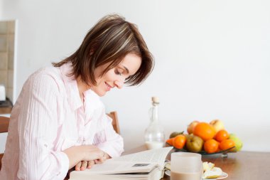 Genç çekici kadın evde, meyve sahip bir kitap okuma, bir