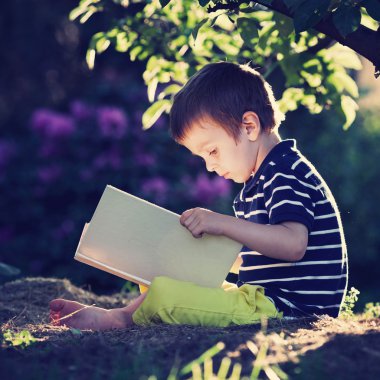 Güzel çocuk çocuk, Bahçe içinde bir kitap okumak, bir t yanında oturan
