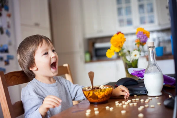 Adorabile bambino, che mangia cereali a colazione guardando — Foto Stock