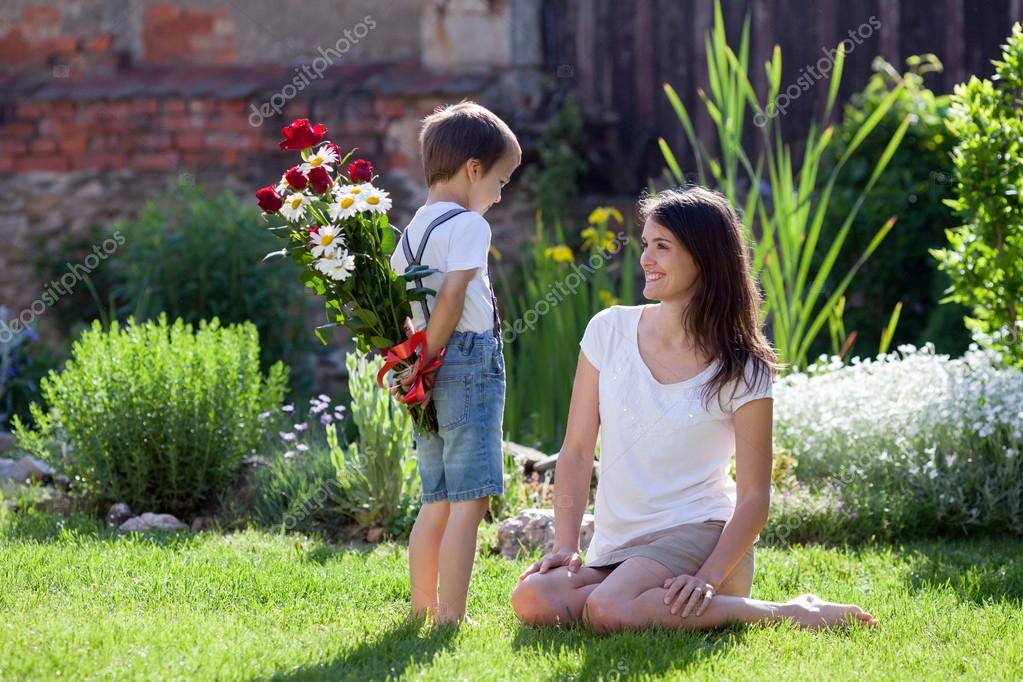 Beautiful kid and mom in spring park, flower and present. Mother