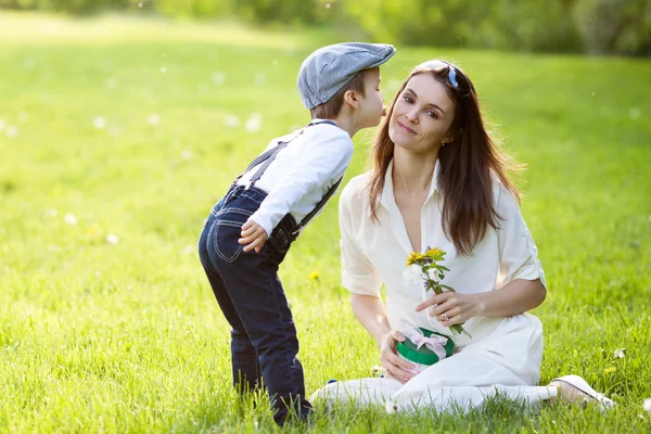 Beautful kid and mom in spring park, flower and present. Mothers — Stock Photo, Image