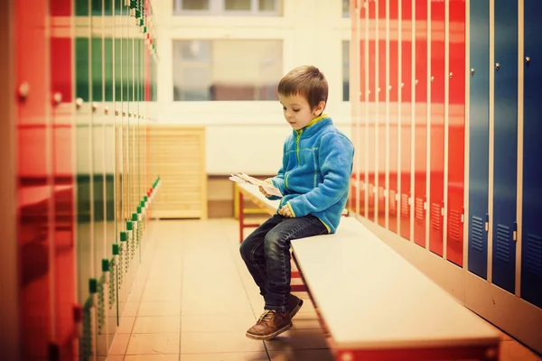 Schattige jongen in een kleedkamer, zittend op een bankje — Stockfoto