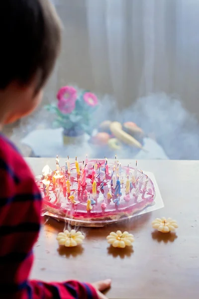 Garoto bonito adorável, soprando velas em um bolo de aniversário — Fotografia de Stock