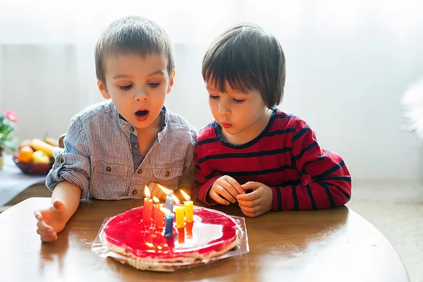 Adoráveis meninos bonitos, soprando velas em um bolo de aniversário — Fotografia de Stock